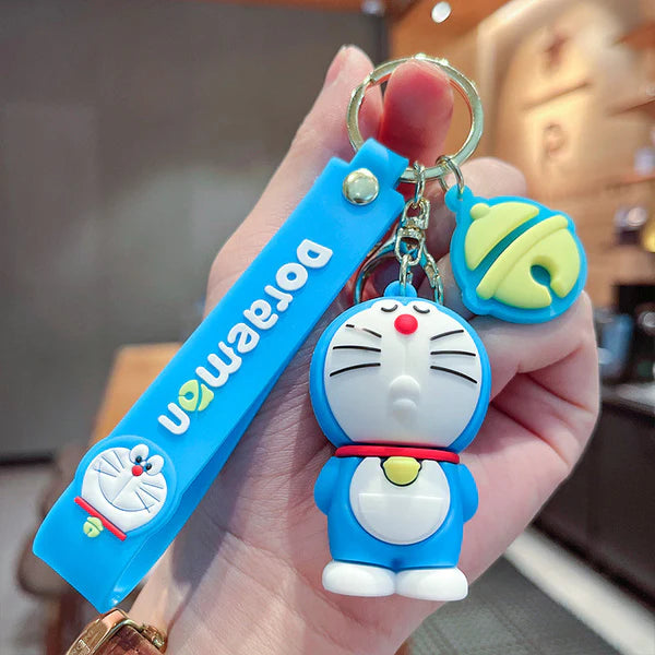 Keychain with Doraemon character held by a hand against a blurred indoor background