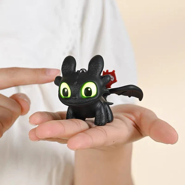 Small black dragon figurine with green eyes held in a hand against a neutral background