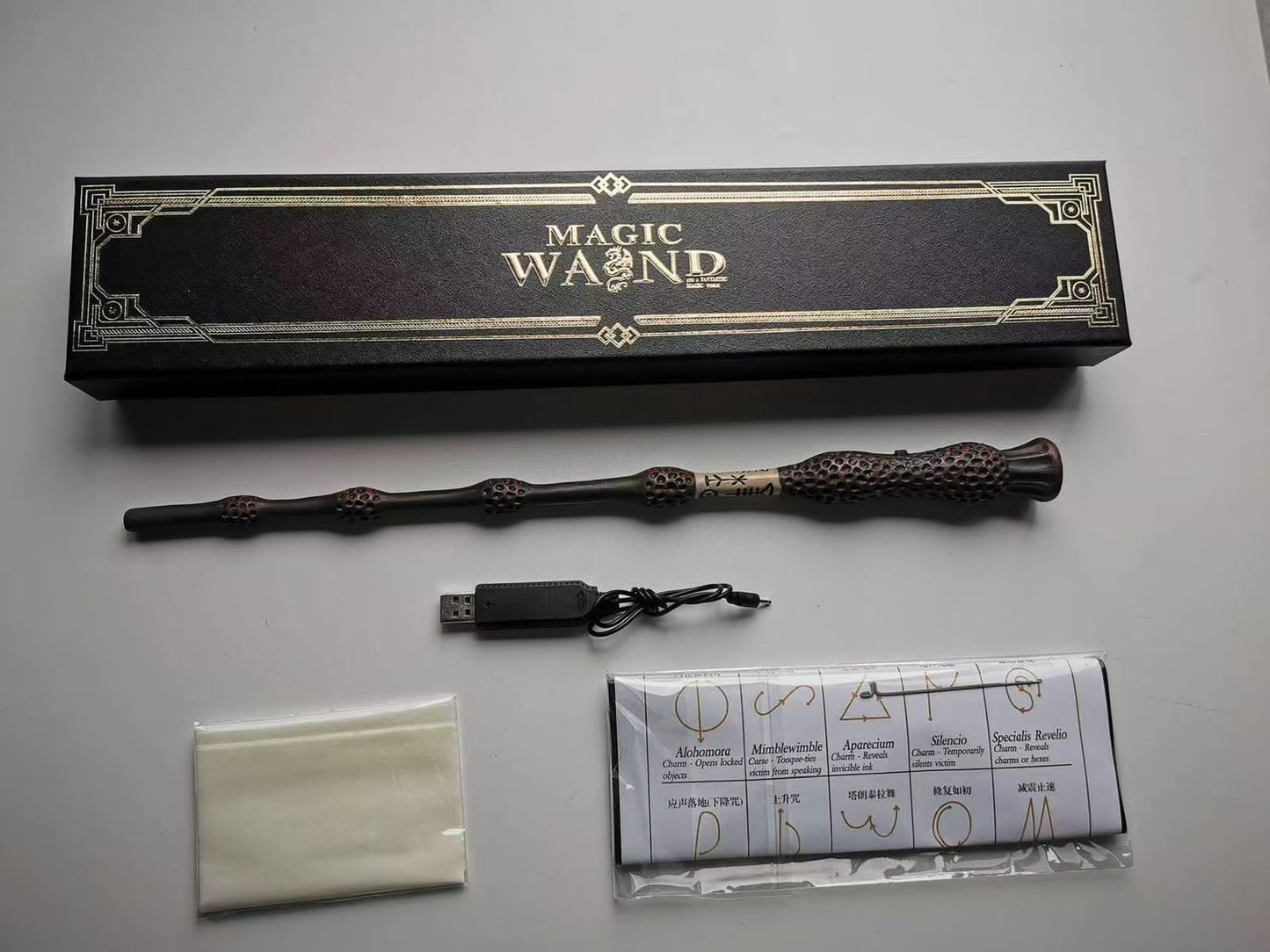 Magic wand with USB cable, cloth, and packaging on a gray surface